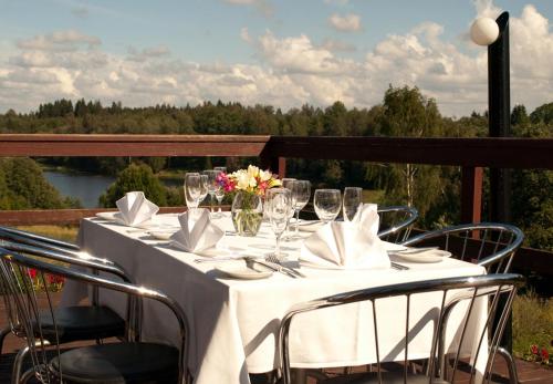 a white table with chairs and wine glasses on a deck at Hotel Sanvilla in Sigulda