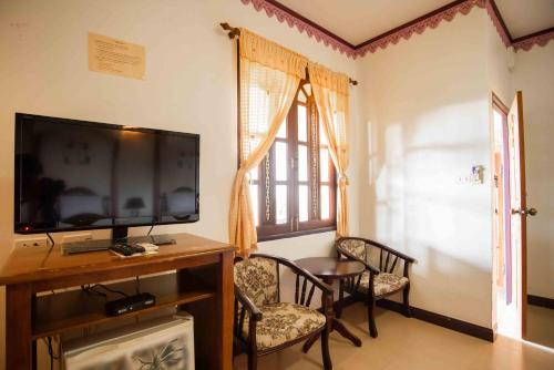 a living room with a flat screen tv and chairs at Ban Ao Thong in Trang