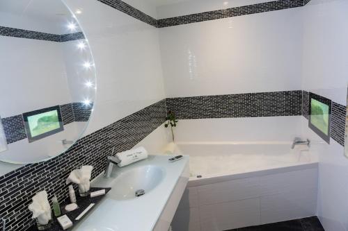 a white bathroom with a tub and a sink at Auberge de Cassagne & Spa in Le Pontet
