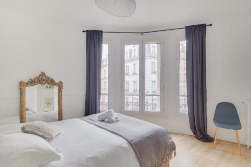 ein Schlafzimmer mit einem großen Bett und einem Spiegel in der Unterkunft Lovely Parisian Flat - Louvre rue St Honoré in Paris