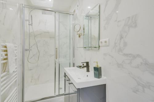 ein weißes Bad mit einer Dusche und einem Waschbecken in der Unterkunft Lovely Parisian Flat - Louvre rue St Honoré in Paris