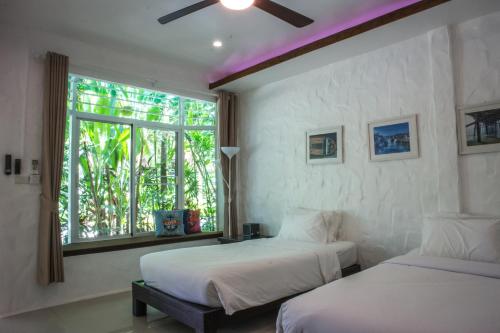 two beds in a room with a window at Parama Koh Chang in Ko Chang