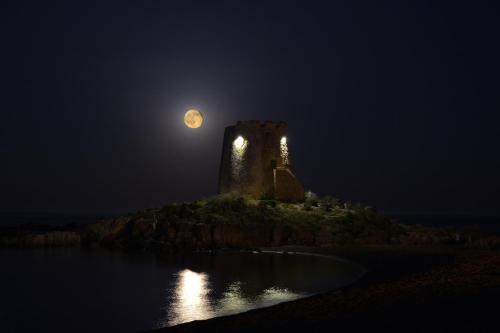 an old castle on an island at night with the moon at B&B Rita and Family in Loceri