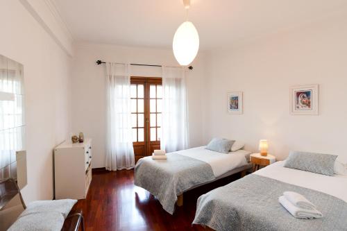 um quarto branco com 2 camas e uma janela em Sintra 23 em Sintra