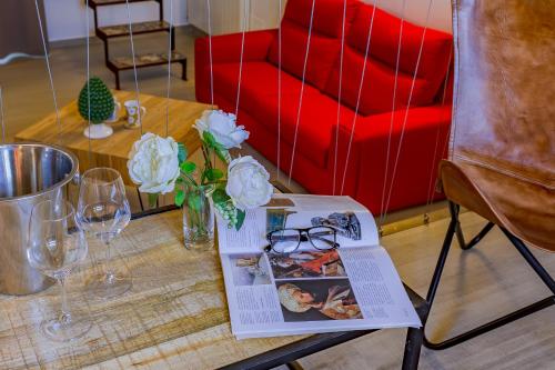 a table with a book and glasses and a red couch at Le Maestranze Deluxe Rooms in Sciacca