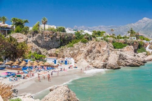a beach with people on the sand and the water at Hostal Luna de Nerja in Nerja