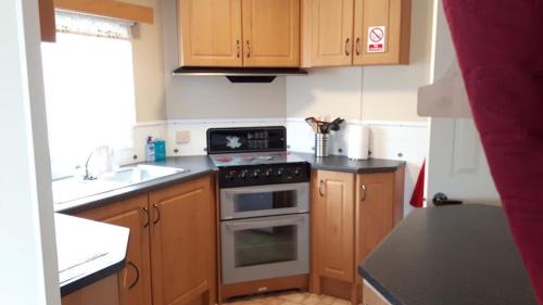 a kitchen with wooden cabinets and a stove top oven at 6 berth on Northshore En-suite Sunnyside in Winthorpe