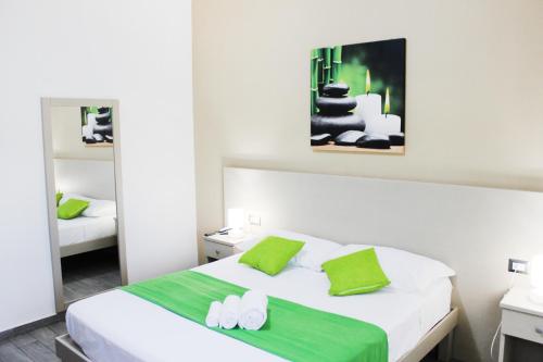 a bedroom with a white bed with a green blanket at Hotel Cesirja in Casavatore