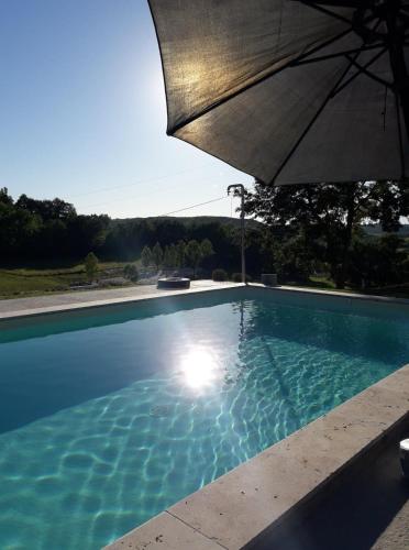 a swimming pool with an umbrella next to it at GITE LA ROCHE in Le Boulvé