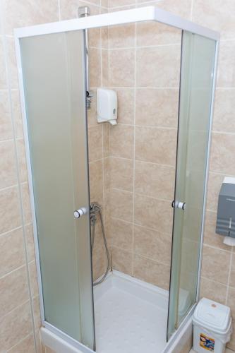 a shower with a glass door in a bathroom at Garni Hotel Lotos in Niš