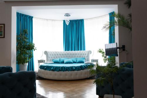 ニシュにあるガルニ ホテル ロトスのリビングルーム(白いソファ、青いカーテン付)