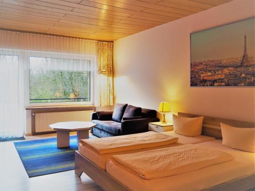 ein Wohnzimmer mit einem Bett und einem Sofa in der Unterkunft Waldhotel Porta Westfalica in Porta Westfalica
