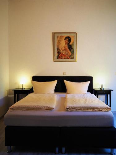 a bed with two pillows and a picture on the wall at Waldhotel Porta Westfalica in Porta Westfalica