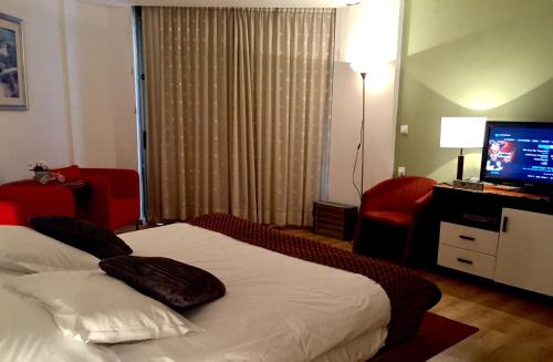 a hotel room with a bed and a television at Raphael Apartments in Herzelia 
