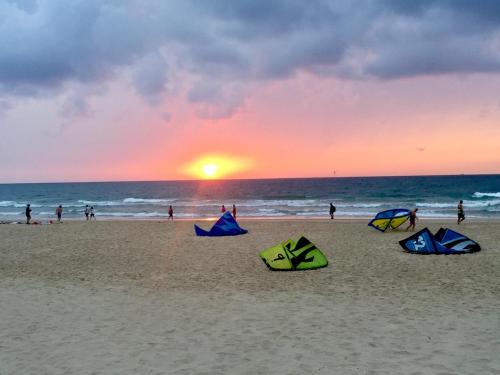 three kites sitting on the beach at sunset at Raphael Apartments in Herzelia 