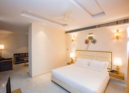 a bedroom with a white bed and a living room at Sapphire Premium Hotel & Suite in Karād