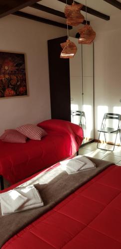 a bedroom with two red beds and two chairs at B&B Pierilu' in Grosseto