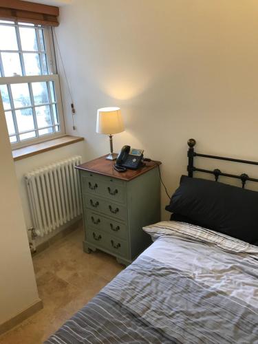 a bedroom with a bed and a lamp on a dresser at The Stables @ The Old Vicarage in Pendeen