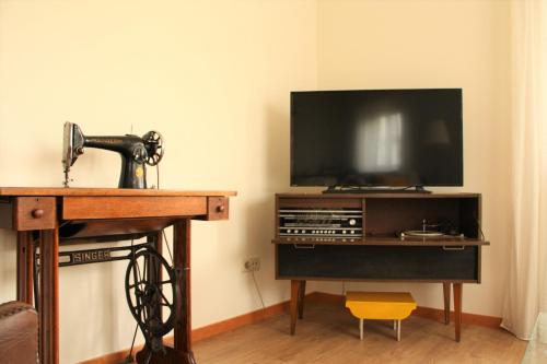 a room with a tv and a sewing machine and a table at Casa Celeste Portugal in Vila Nova de Gaia