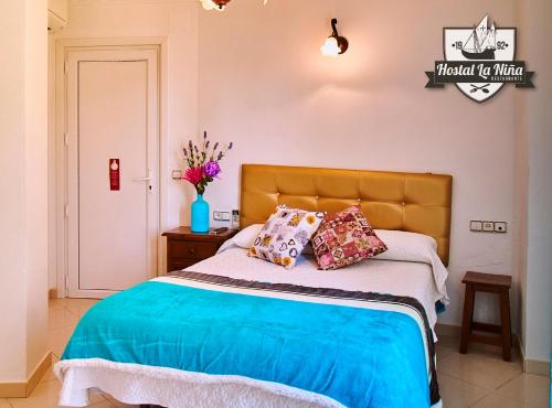a bed in a bedroom with a white bedspread at Hostal Restaurante La Niña in Palos de la Frontera