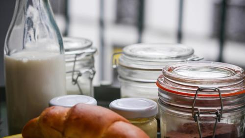 a table with jars and a plate of bread and a bottle of milk at Casa das Arcadas in Ponta Delgada