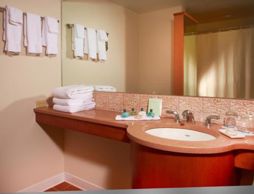 a bathroom with a sink and a mirror and towels at The Penn Stater Hotel and Conference Center in State College