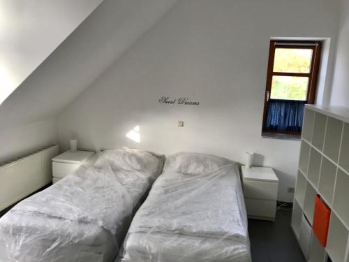 Cette chambre comprend un lit avec des draps blancs. dans l'établissement Ferienwohnung Holtenau, à Altenholz