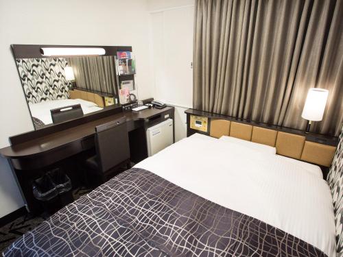 a hotel room with a bed and a night stand at APA Hotel Hakodate Ekimae in Hakodate
