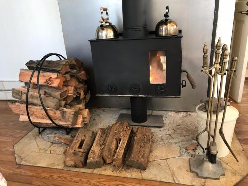 a black stove with a pile of fire wood at Petit Hotel Kurumi to Milk in Tateshina