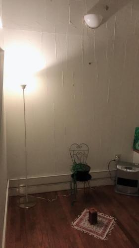 a room with a white wall with a lamp and a table at Petit Hotel Kurumi to Milk in Tateshina