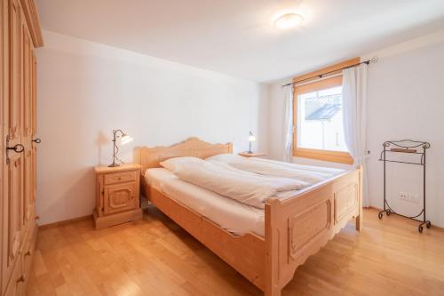 une chambre avec un lit en bois et une fenêtre dans l'établissement LAAX Homes - Capolgarten 3,7, à Flims