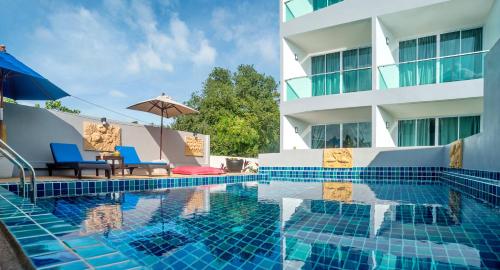a pool with two chairs and an umbrella next to a building at The Tree Samui in Bophut 