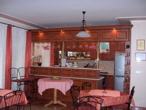 a kitchen with a bar with pink tables and chairs at Harmónia Panzió in Sárospatak