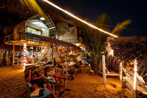 a group of people sitting outside of a restaurant at night at Bara Beach Home in Galle