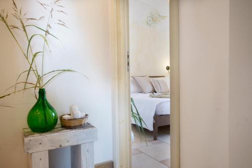 a room with a bed and a green vase on a table at Le Gioie - Villa Macchia Mediterranea - Splendida villa vista mare immersa nel verde in Torre Pali 