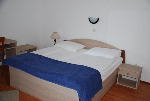um quarto com uma cama com um cobertor azul em Apartmani Dragica em Rab