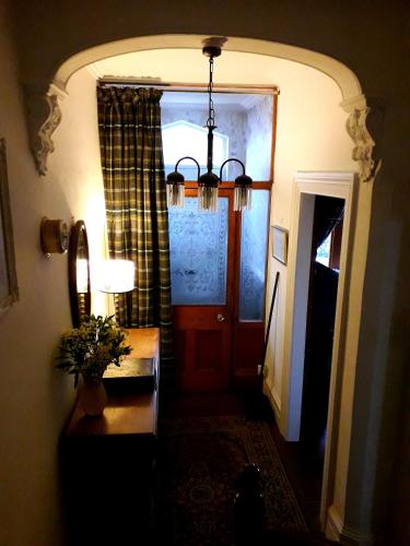 a hallway with a red door and a table with a lamp at Tŷ Selah, Rugby Ave, Neath in Neath