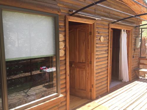 a wooden cabin with a large window and a door at Hermosa Casa Pisco Elqui in Pisco Elqui