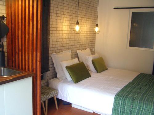 a bedroom with a bed with green and white pillows at Small Loft in Cascais
