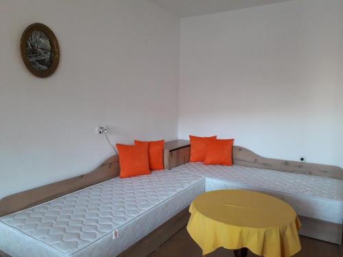 ポモリエにあるMavrova Guest Houseのベッド(オレンジ&イエローの枕付)、時計が備わります。