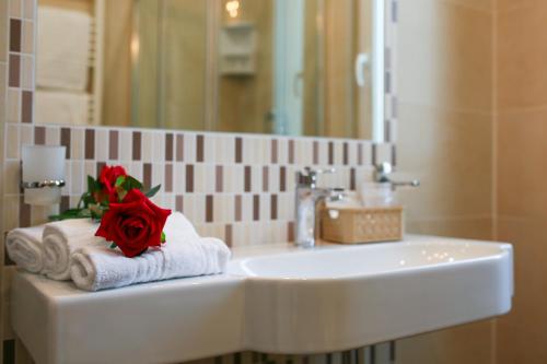 un lavandino in bagno con una rosa rossa sopra gli asciugamani di Hotel Bergamo a Rimini