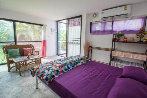 a bedroom with a purple bed in a room with windows at Phor Kub Mae Homestay in Damnoen Saduak