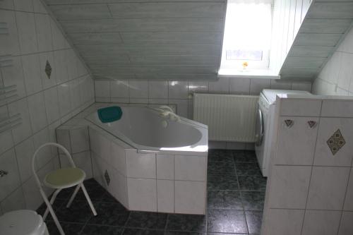 baño blanco pequeño con bañera y ventana en Ferienwohnung "Küchenmeister" en Schlettau