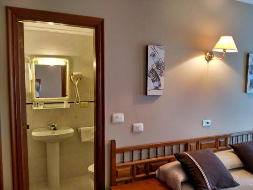 um quarto com uma cama, um lavatório e um espelho em Hotel Xeito em Combarro