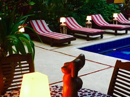 a cat sitting on a table next to chairs next to a pool at Maison Couleur Passion in Nianing