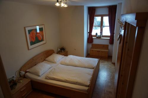a bedroom with a bed with white sheets and a window at Haus Johannes in Wagrain