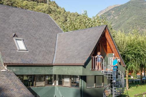 two people standing on a balcony of a house at Bungalows Verneda Mountain Resort in Arrós