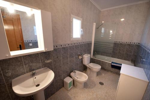een badkamer met een wastafel, een toilet en een spiegel bij Villa Isabel in Murcia