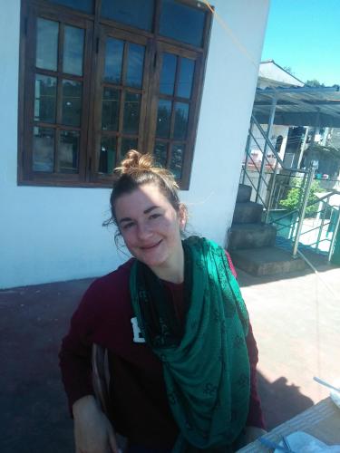 a woman wearing a green scarf sitting in front of a building at Top View in Hatton