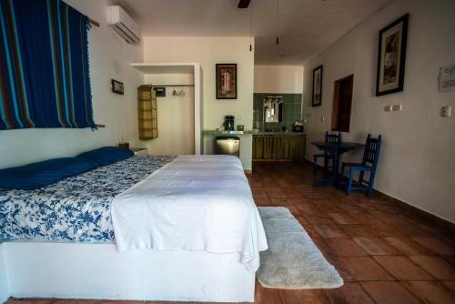 a bedroom with a white bed and a kitchen at Hotel Boutique Skulls Landing in Isla Mujeres